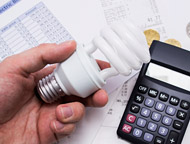 Person holding LED light bulb with calculator