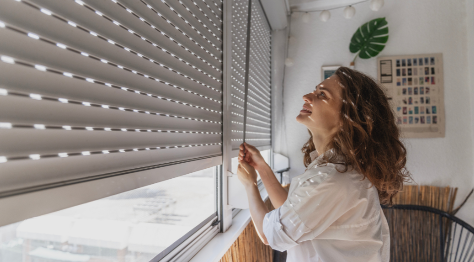 Woman closes blinds to block sun on summer day
